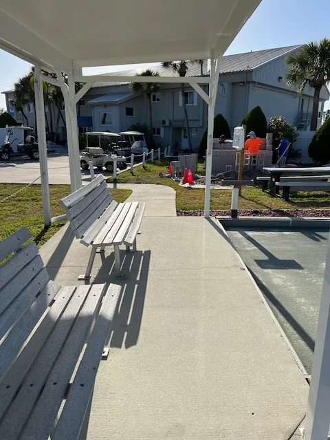 White covered walkway with benches beside an outdoor court.