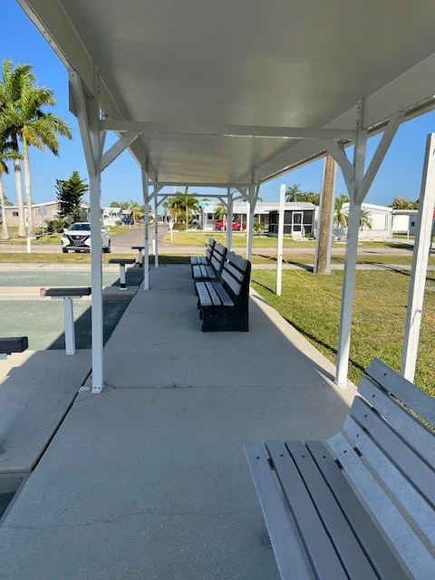 Benches and white support posts along a covered outdoor walkway.
