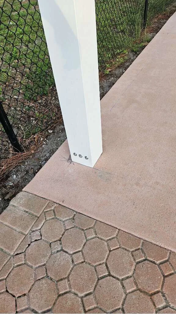 White support post beside a concrete surface and hexagonal pavers.